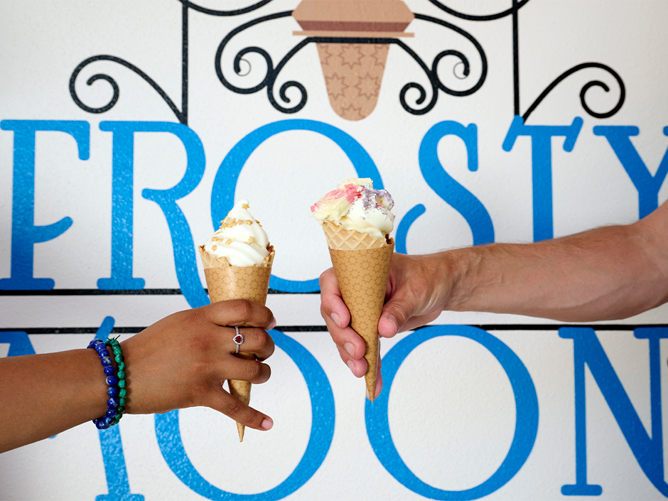 Two hands holding out ice cream cones from Frosty Moon in Celestial Park at Epic Universe