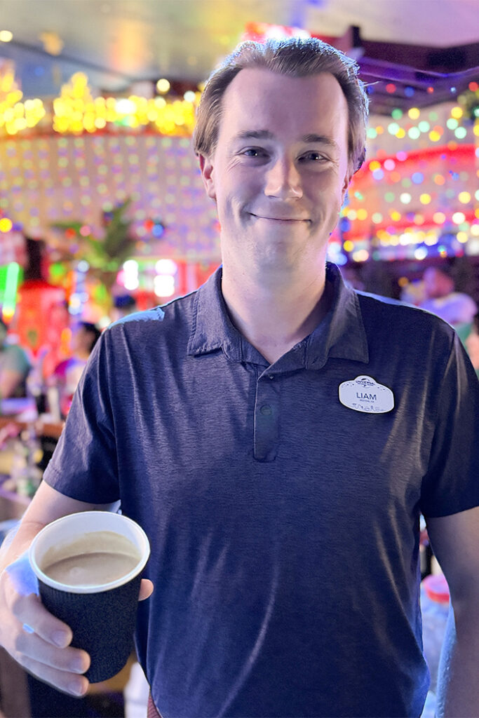 Liam Wedderburn, beverage program assistant manager, holds the Hot Buttered Rum out toward the camera
