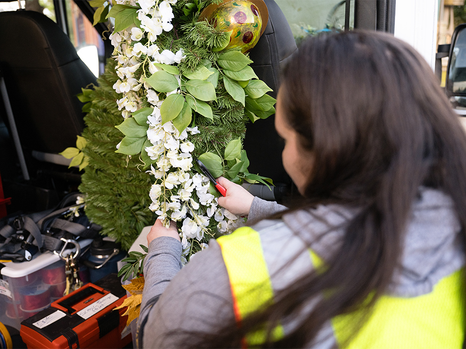 A Team Member works to attach garland to a building in Celestial Park